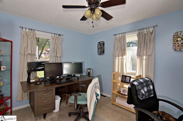 office space with a textured ceiling, light colored carpet, and ceiling fan