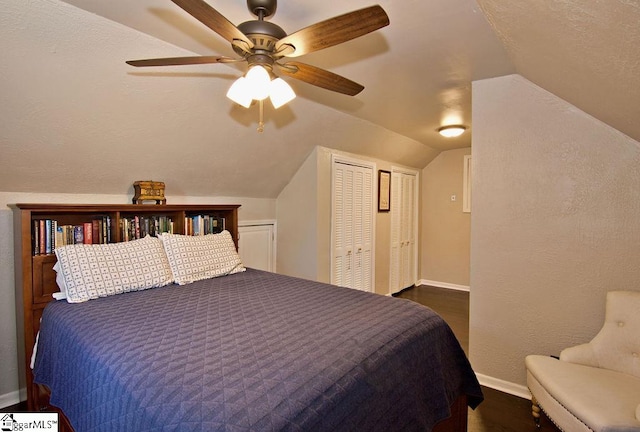 bedroom featuring ceiling fan, multiple closets, and vaulted ceiling