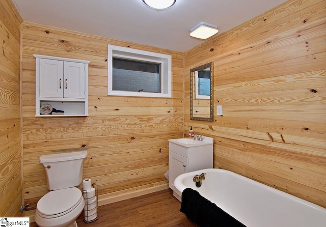 bathroom featuring hardwood / wood-style flooring, wooden walls, toilet, and a washtub