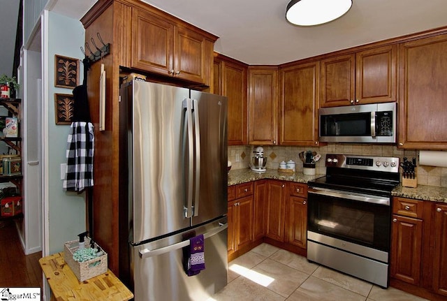 kitchen with tasteful backsplash, light stone countertops, and appliances with stainless steel finishes