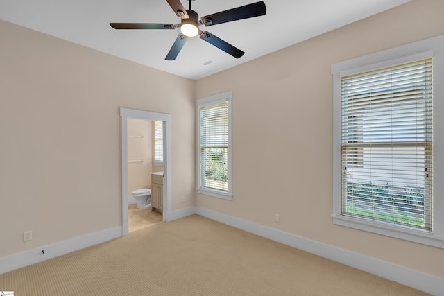 unfurnished bedroom featuring ceiling fan, light colored carpet, and ensuite bathroom