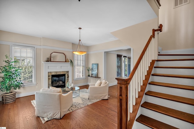 living room with wood-type flooring and a tiled fireplace