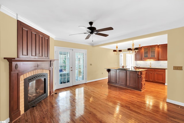 kitchen with ornamental molding, light wood-type flooring, a fireplace, and a center island