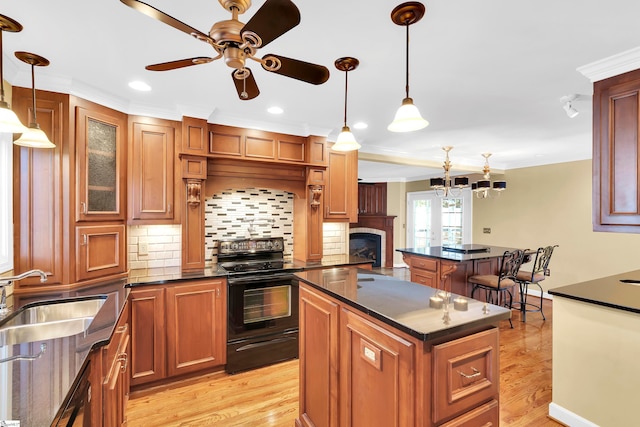 kitchen featuring hanging light fixtures, black range with electric cooktop, sink, and a kitchen island