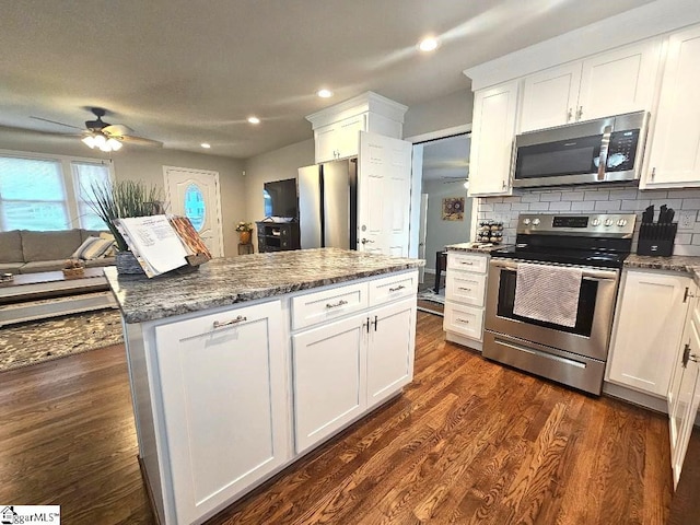 kitchen featuring white cabinetry, appliances with stainless steel finishes, dark stone countertops, backsplash, and dark hardwood / wood-style flooring