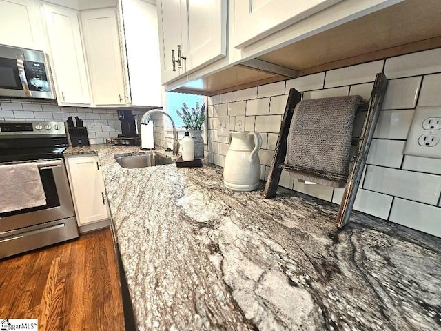 kitchen featuring sink, dark hardwood / wood-style floors, light stone countertops, white cabinetry, and appliances with stainless steel finishes