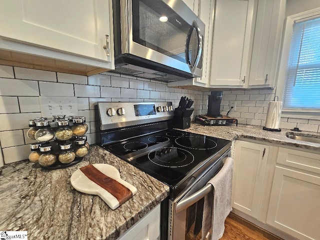 kitchen featuring tasteful backsplash, white cabinetry, appliances with stainless steel finishes, and light stone counters