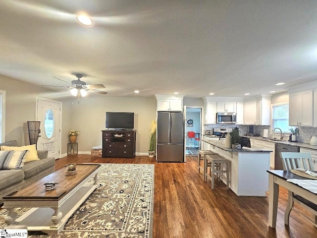 living room featuring ceiling fan, sink, and dark hardwood / wood-style flooring