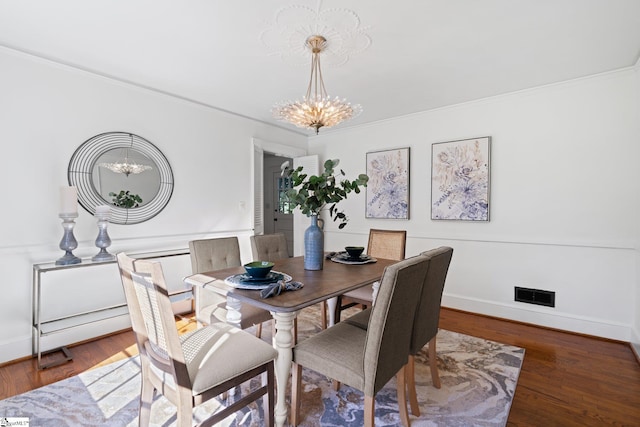 dining area with ornamental molding, a chandelier, and dark hardwood / wood-style floors