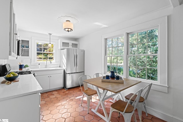 kitchen featuring crown molding, appliances with stainless steel finishes, hanging light fixtures, sink, and white cabinets