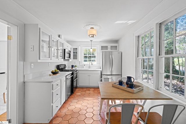 kitchen with sink, appliances with stainless steel finishes, ornamental molding, decorative light fixtures, and white cabinets