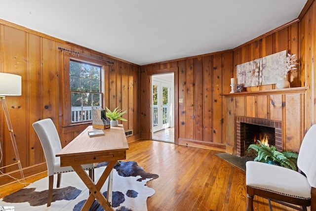 office area featuring wood walls, light wood-type flooring, and a fireplace