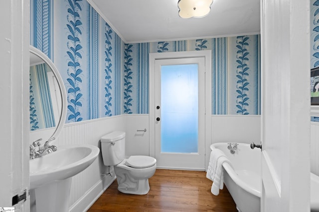 bathroom featuring a bath, hardwood / wood-style flooring, toilet, and sink