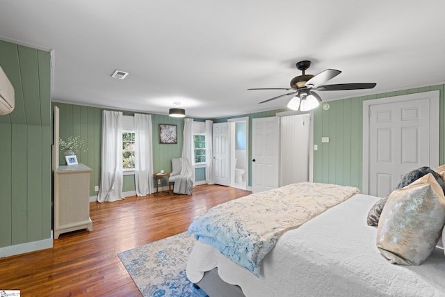 bedroom featuring hardwood / wood-style flooring, wood walls, and ceiling fan