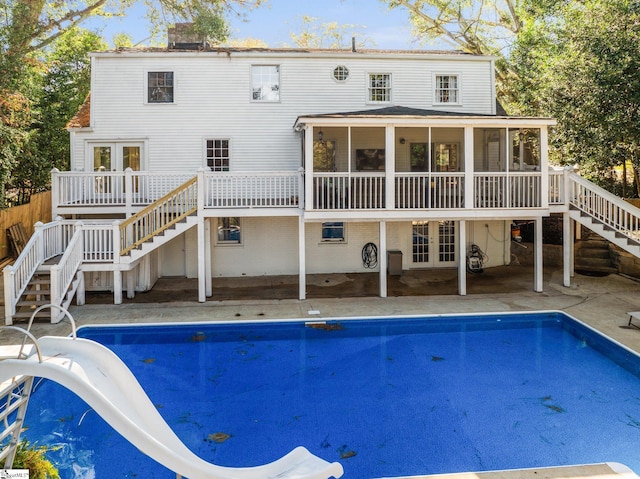 rear view of house featuring a sunroom, a swimming pool side deck, and french doors