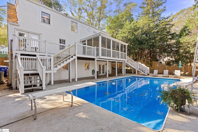 view of swimming pool with a diving board, a sunroom, a patio, and a wooden deck