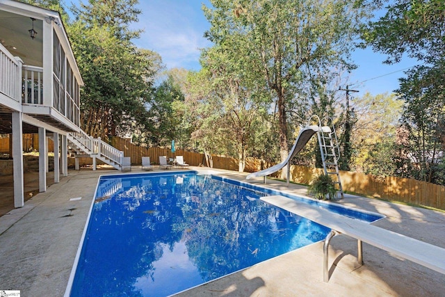 view of pool featuring a water slide, a sunroom, a diving board, and a patio