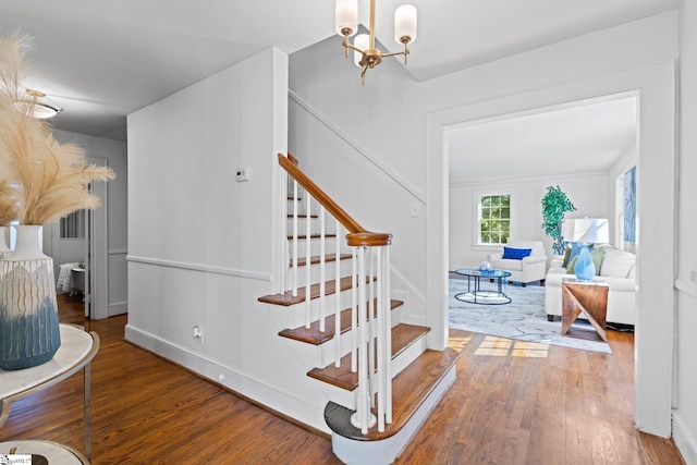 stairway with hardwood / wood-style floors and a chandelier