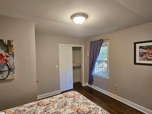 bedroom with dark wood-type flooring and a closet