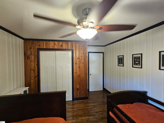 bedroom featuring dark wood-type flooring, wood walls, ceiling fan, and crown molding