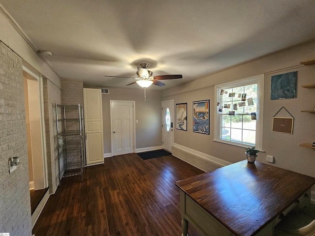 unfurnished living room featuring dark hardwood / wood-style flooring, brick wall, and ceiling fan