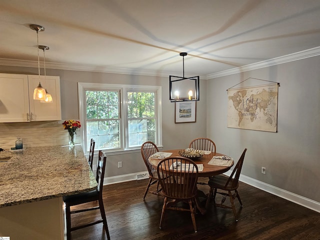 dining space with dark hardwood / wood-style flooring, crown molding, and an inviting chandelier