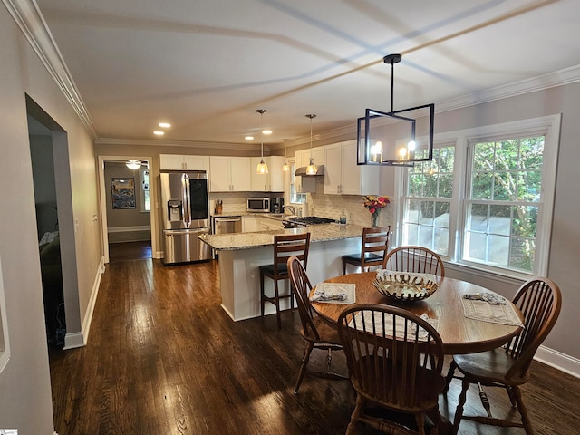 dining room with dark hardwood / wood-style flooring, a chandelier, sink, and crown molding