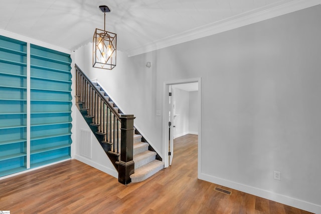 staircase featuring an inviting chandelier, hardwood / wood-style flooring, and crown molding