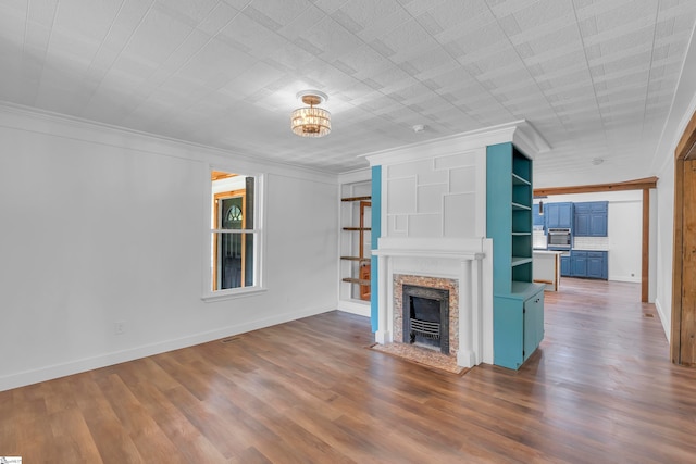 unfurnished living room with hardwood / wood-style floors, a high end fireplace, and ornamental molding