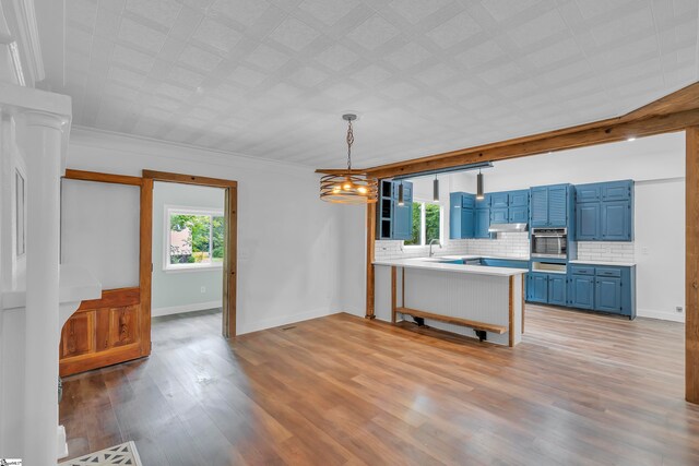 kitchen featuring light hardwood / wood-style floors, kitchen peninsula, decorative light fixtures, blue cabinetry, and stainless steel oven