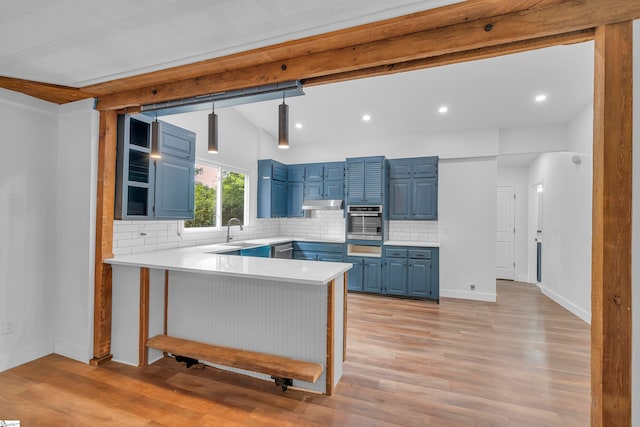 kitchen featuring stainless steel appliances, kitchen peninsula, blue cabinetry, pendant lighting, and light wood-type flooring