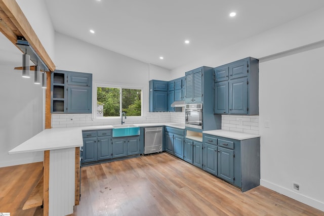 kitchen with stainless steel appliances, sink, light hardwood / wood-style flooring, lofted ceiling, and blue cabinets