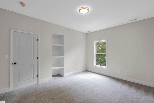 carpeted empty room featuring built in shelves