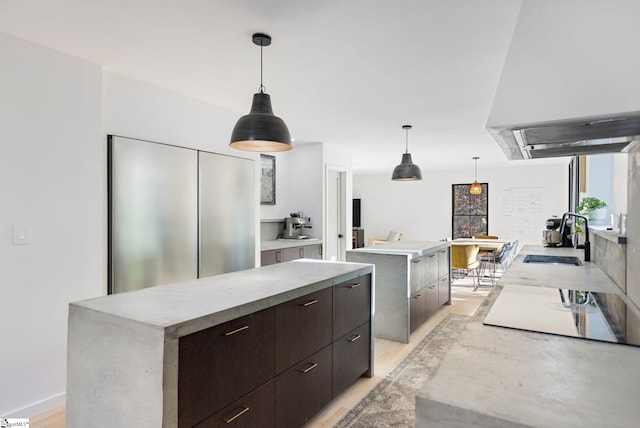 kitchen with decorative light fixtures, light wood-type flooring, sink, and a spacious island