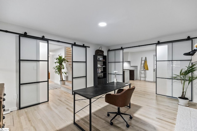 office space featuring light wood-type flooring and a barn door