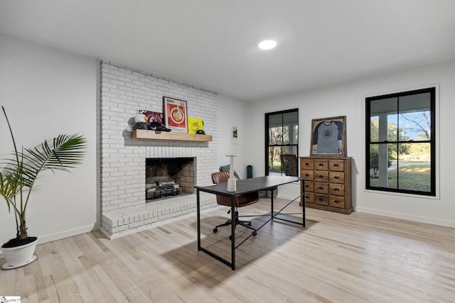 office space featuring light hardwood / wood-style flooring and a brick fireplace