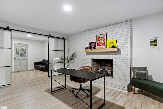 living room featuring a barn door, light hardwood / wood-style floors, and a fireplace