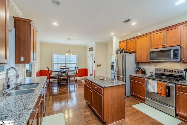 kitchen featuring light stone counters, stainless steel appliances, sink, and a kitchen island