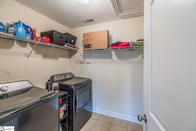 clothes washing area with light tile patterned flooring and separate washer and dryer