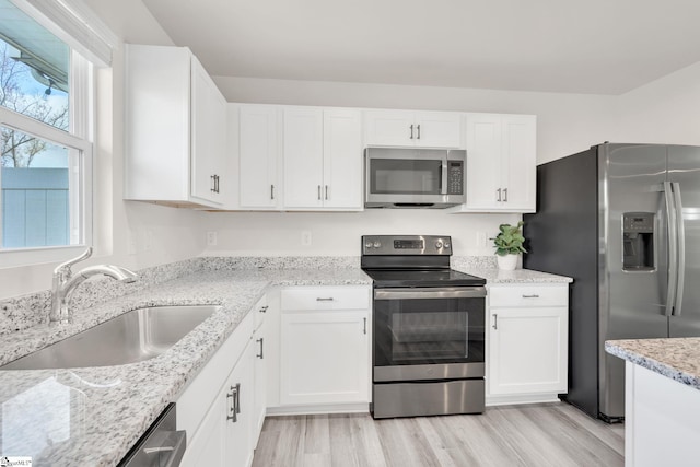 kitchen with white cabinetry, sink, stainless steel appliances, and light hardwood / wood-style floors