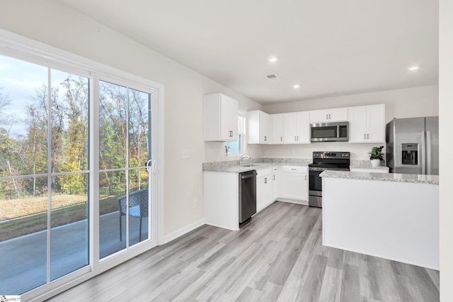 kitchen featuring light stone countertops, appliances with stainless steel finishes, sink, light hardwood / wood-style flooring, and white cabinets