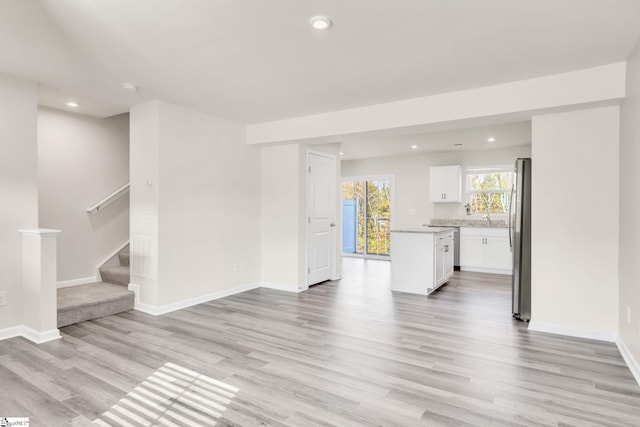 unfurnished living room featuring light hardwood / wood-style flooring and sink