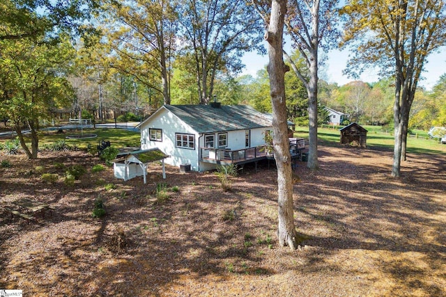 back of property featuring a storage shed and a wooden deck