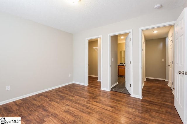 unfurnished bedroom featuring dark wood-type flooring, a closet, and a spacious closet