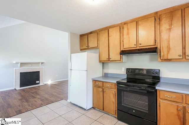 kitchen featuring a fireplace, light wood-type flooring, white refrigerator, a textured ceiling, and black range with electric stovetop