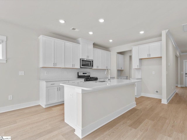 kitchen with a center island with sink, white cabinets, sink, and appliances with stainless steel finishes