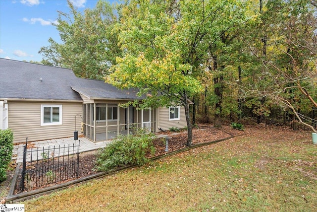 back of property with a lawn, a sunroom, and a patio