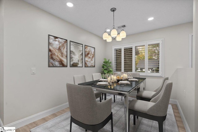 dining space with a textured ceiling, a chandelier, and hardwood / wood-style flooring