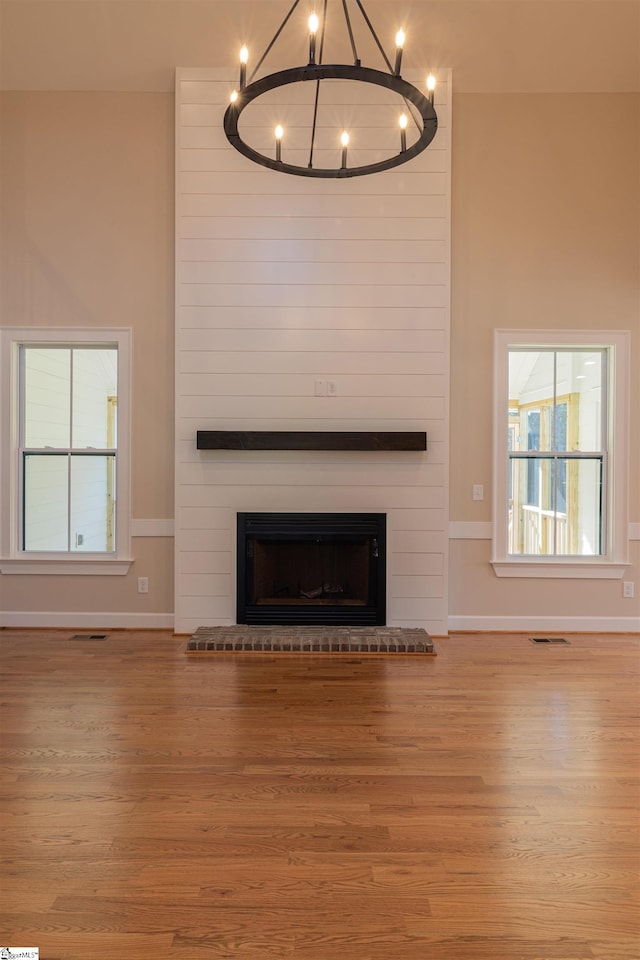 unfurnished living room with a fireplace, light hardwood / wood-style floors, and an inviting chandelier