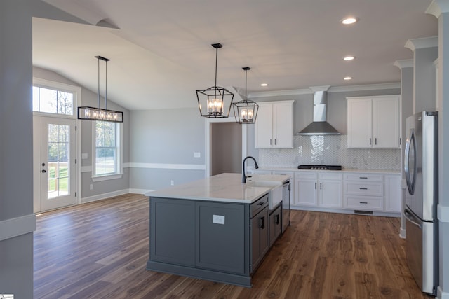 kitchen featuring white cabinetry, wall chimney range hood, dark hardwood / wood-style floors, decorative light fixtures, and appliances with stainless steel finishes